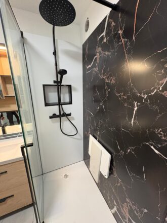 Vue zoomée d'une douche à l'italienne PMR avec paroi effet marbre par Eau et Design rénovation de salle de bain