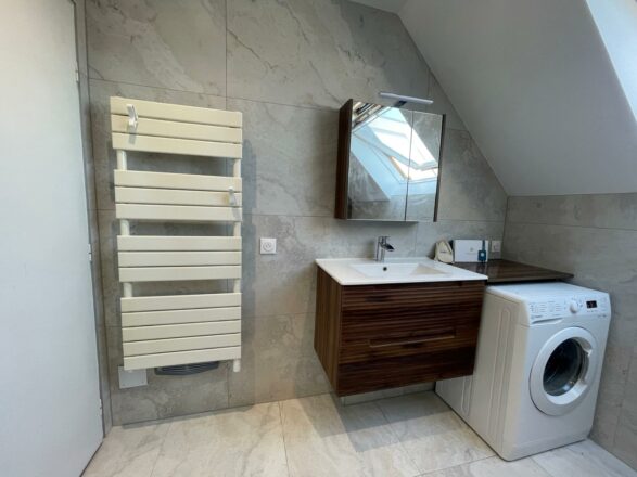 Salle de bain sous comble vue du meuble vasque élégant avec le lave linge