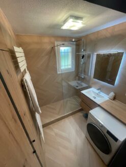Vue depuis l'entrée de la rénovation salle de bain zen Illkirch carrelage bois Kerakom douche à l'italienne et placard bois sur mesure par Eau et Design